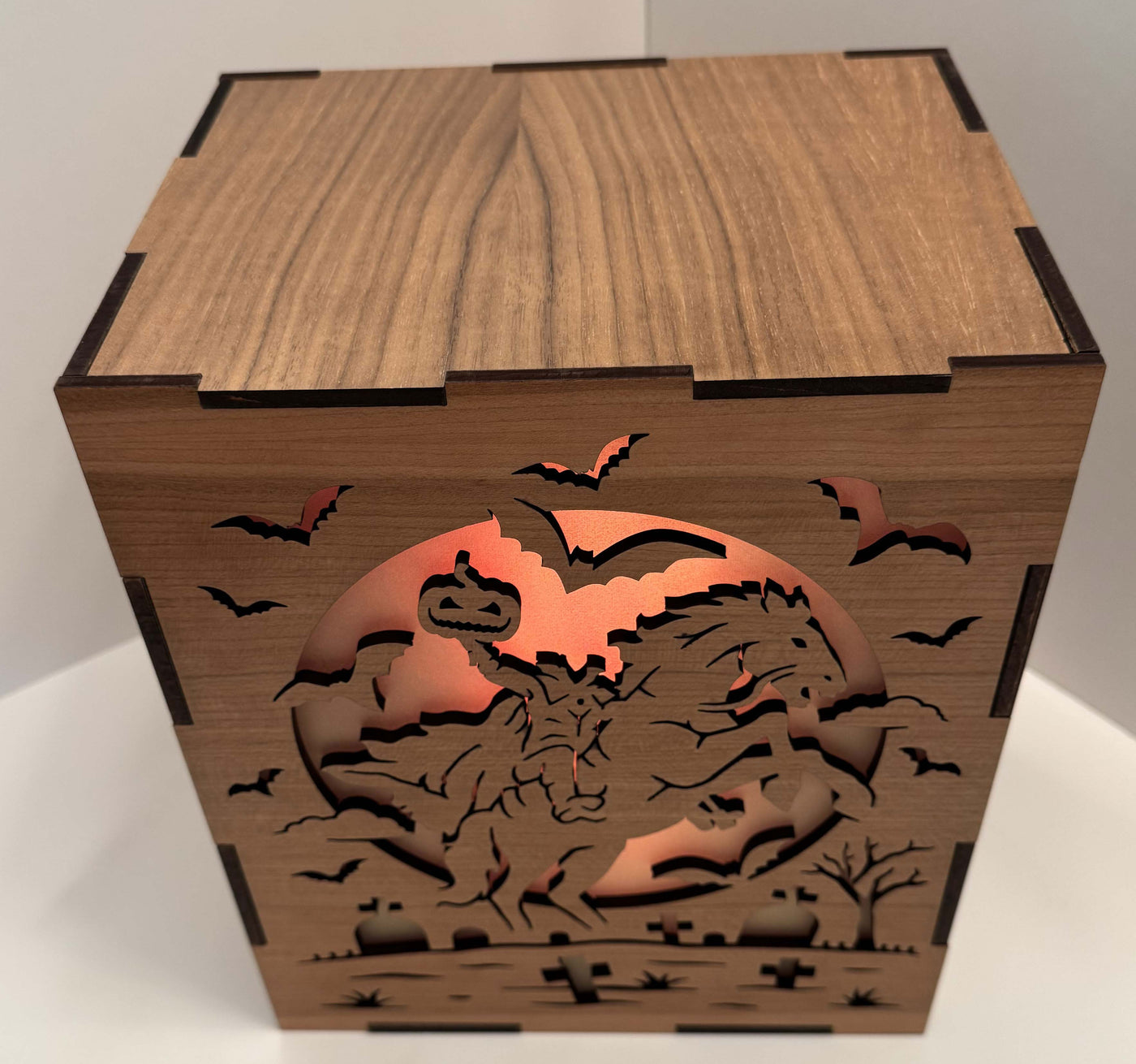 Halloween-themed decorative box with a headless horseman in a graveyard with a pumpkin for a head, and bats against an orange moonlit sky.